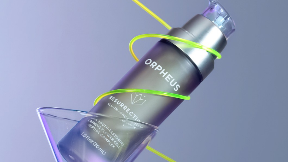 Serum for Dull Skin - Orpheus Resurrection skincare serum bottle artistically displayed in a tilted martini glass with neon light accents, highlighting product vibrancy.